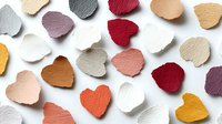 Colorful leather heart shapes scattered on white background. Craft supplies for DIY projects, scrapbooking, card making. Valentine's Day decorations isolated.