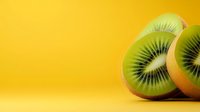 Fresh kiwi fruit slices on vibrant yellow background showing green flesh and black seeds for healthy eating and nutrition concepts.