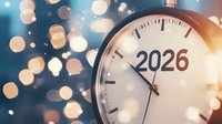 Clock showing 2026 with blurred festive bokeh lights in blue and gold tones, symbolizing future time, celebration and new year countdown approaching midnight.