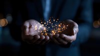 Magical glowing golden sparkles and light particles floating above cupped hands in dark background, creating mystical atmosphere for spiritual and fantasy concepts.