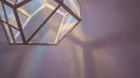 Modern geometric pendant lamp casting warm light and shadows on purple wall, suitable for interior design and home decor projects.