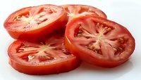 Fresh red tomato slices showing juicy pulp and seeds on white background, macro photography highlighting natural texture and vibrant color for food design.