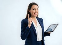 Professional businesswoman in navy suit holding tablet with finger raised in eureka gesture on white background for corporate presentations.