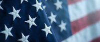 American flag with white stars on blue field and red stripes in soft focus background for patriotic holidays and national celebrations.