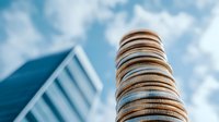 Stack of shiny coins against modern glass building and blue sky with clouds, representing financial growth, investment and corporate success.