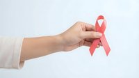 Hand holding pink ribbon symbol for breast cancer awareness campaign on white background isolated for healthcare design and medical support concepts.