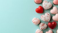 Heart shaped candies and chocolates with red and pink decorative coating arranged on mint blue background with copy space for Valentine's day message.