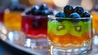 Fresh layered fruit dessert with orange jelly, kiwi slices and blueberries in glass, colorful sweet treat served at party or restaurant, selective focus.