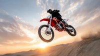 Motocross rider jumping red dirt bike against dramatic sunset sky with clouds. Extreme sports action shot capturing freedom and adrenaline rush in desert landscape.