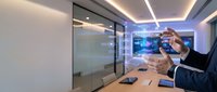 Businessman using VR headset in modern office conference room with glass walls and ambient lighting for virtual reality business presentations.