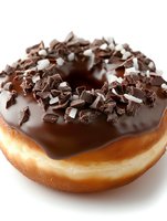 Fresh donut with dark chocolate glaze topped with chocolate shavings and pieces on white background, close-up view for bakery and dessert menu promotion.