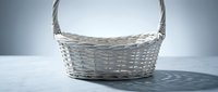 Empty wicker basket with handle on white surface against gray background for storage and home organization projects.