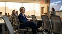 Professional businesswoman attending corporate presentation in modern conference room with colleagues listening to speaker.