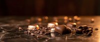 Scattered chocolate pieces and cocoa nibs on dark surface with warm bokeh lighting, suitable for food and beverage marketing materials.
