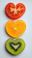 Heart-shaped fruit slices arranged vertically - red tomato, orange citrus, and green kiwi on white background. Healthy eating concept for Valentine's Day.