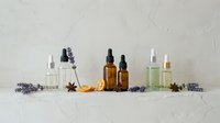 Natural aromatherapy essential oil bottles with lavender flowers and spices on white marble surface for wellness spa treatment and relaxation therapy.