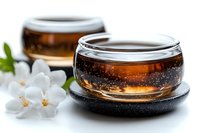 Aromatic jasmine tea served in traditional glass cups with fresh white jasmine flowers and black coasters, creating tranquil Asian tea ceremony atmosphere.