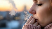 Young Caucasian woman exhaling warm breath in cold winter air at sunset, wearing knit sweater, side profile view showing contemplative peaceful expression.