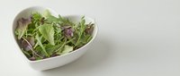 Fresh mixed salad greens and microgreens in white bowl on neutral background, suitable for food, nutrition, healthy eating, restaurant menus, and wellness content.