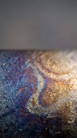 Colorful oil spill rainbow reflection on wet asphalt pavement surface with shallow depth of field and blurred background for environmental concepts.