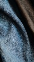 Close-up macro shot of blue denim and brown leather fabric textures with detailed weave patterns and natural material surfaces for fashion design projects.