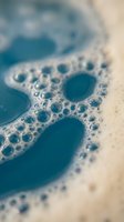 Macro shot of blue soapy foam with delicate bubbles and water droplets, creating an abstract texture of cleanliness and freshness.