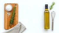 Culinary flat lay with olive oil bottle, rosemary herbs, sea salt on wooden cutting board and kitchen utensils for cooking and food preparation.