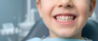 Young child with braces smiling during orthodontic dental appointment showing metal brackets on teeth in modern clinic setting for oral health care.