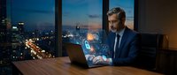 Mature Caucasian businessman in suit working on laptop with glowing cybersecurity hologram icons at night office, city lights background.