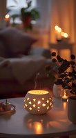 Glowing ceramic aroma diffuser with incense smoke in cozy evening interior setting, warm bokeh lights and houseplants creating relaxing atmosphere.