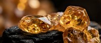 Raw amber gemstones with natural inclusions resting on dark coal surface creating striking contrast for jewelry making and geological study purposes.