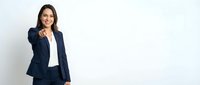 Professional businesswoman in navy suit pointing forward with confident smile against white background for corporate marketing materials.