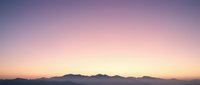 Serene mountain silhouette against gradient twilight sky transitioning from purple to pink to golden yellow at horizon for peaceful nature backgrounds.