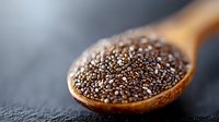 Organic chia seeds in wooden spoon on dark background, macro shot of healthy superfood rich in omega-3 fatty acids and fiber, food photography.
