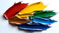 Vibrant oil paint smears in rainbow colors arranged diagonally on white canvas, showing rich texture and artistic brushstrokes for creative background design.