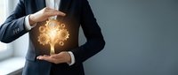 Professional businessman in dark suit protecting glowing golden tree with gear mechanisms symbolizing business growth, innovation and sustainable development.