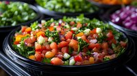 Fresh chopped vegetables and herbs mixed in colorful salad with tomatoes, bell peppers, onions and parsley in black container, ready to serve food.