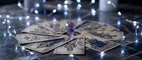 Mystical tarot cards spread with amethyst crystal and fairy lights creating magical fortune telling atmosphere for spiritual guidance and divination practices.