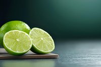 Fresh cut lime halves on wooden cutting board against dark background with copy space, close up view showing juicy citrus fruit texture.