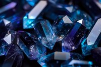 Blue and purple crystal gemstones with prismatic light reflections creating luxury jewelry and mineral collection background for premium designs.