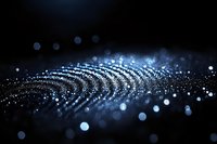 Glowing blue particles forming wave pattern on dark background with bokeh light effect and shimmering dust, creating futuristic abstract composition.