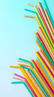 Colorful eco-friendly bamboo and paper drinking straws scattered on turquoise background for sustainable beverage service and zero waste lifestyle.