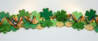 St. Patrick's Day festive border with green shamrocks, gold coins and Irish flag ribbon on white background for holiday decorations and greeting cards.