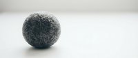 Gray wool felt ball on white surface with soft lighting for crafting and DIY projects. Natural fiber sphere isolated on clean background for creative designs.