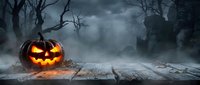 Glowing jack-o-lantern pumpkin on wooden surface in spooky Halloween forest with bare trees and misty atmosphere for seasonal decorations.