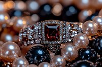 Elegant engagement ring with square brown gemstone surrounded by diamonds, nestled among black and pink pearl necklaces creating luxurious jewelry composition.