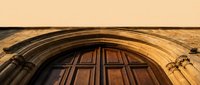 Historic stone archway with ornate wooden doors featuring traditional paneled design and carved architectural details for heritage building projects.