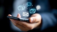 Hand holding smartphone with glowing social media and communication icons floating above screen, illustrating digital connectivity and mobile messaging.