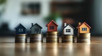 Small model houses placed on stacks of coins showing real estate investment, property market growth, and mortgage costs concept on wooden surface with blurred background.