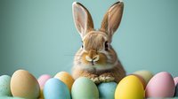 Adorable brown bunny rabbit with long ears peeking over colorful pastel Easter eggs arranged in row against mint green background. Spring holiday celebration concept.